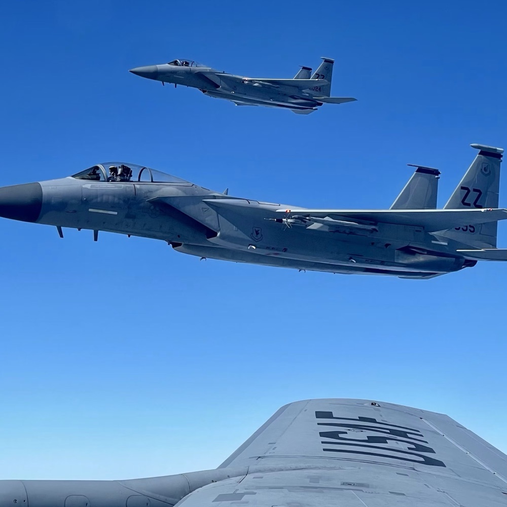 Two fighter aircraft flying in close formation against a deep blue sky