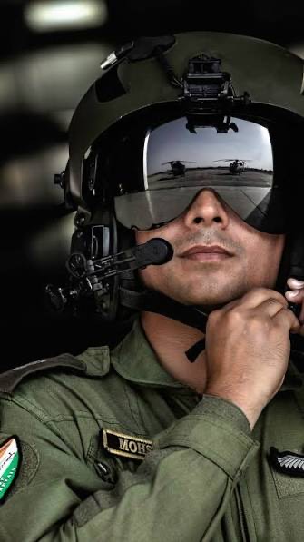 An air force aviator wearing a flight helmet and visor, adjusting the helmet strap