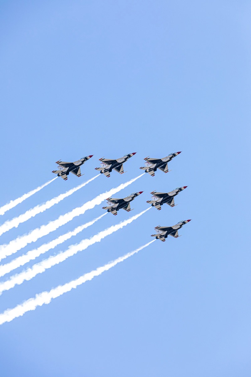 A formation of jet aircraft climbing steeply against a clear pale blue sky